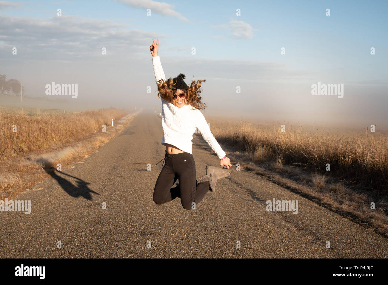 Jeune femme faisant un saut sur une case vide et selfies route brouillard tôt le matin Banque D'Images