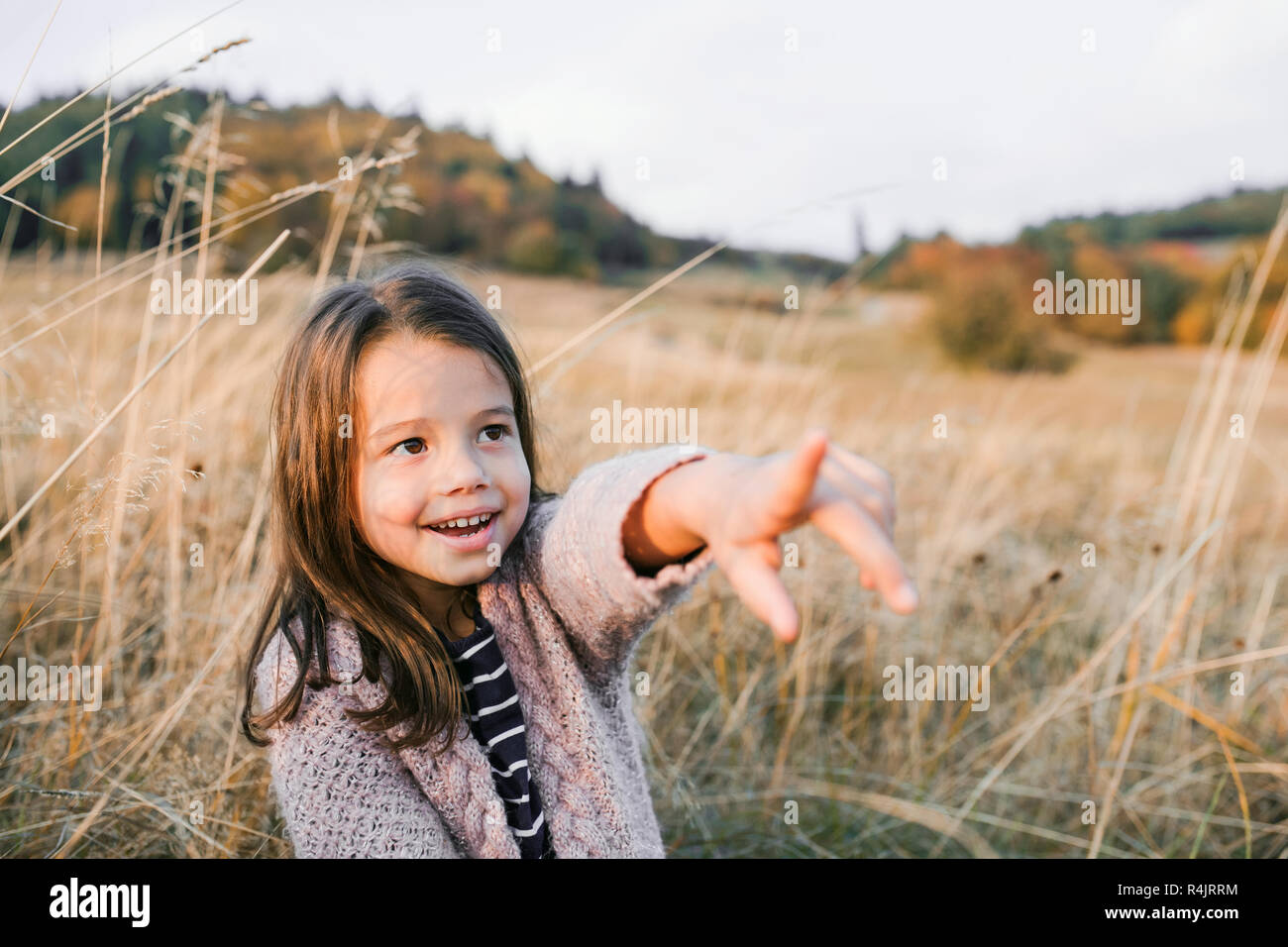 Une petite fille debout dans automne nature, doigt sur quelque chose. Banque D'Images