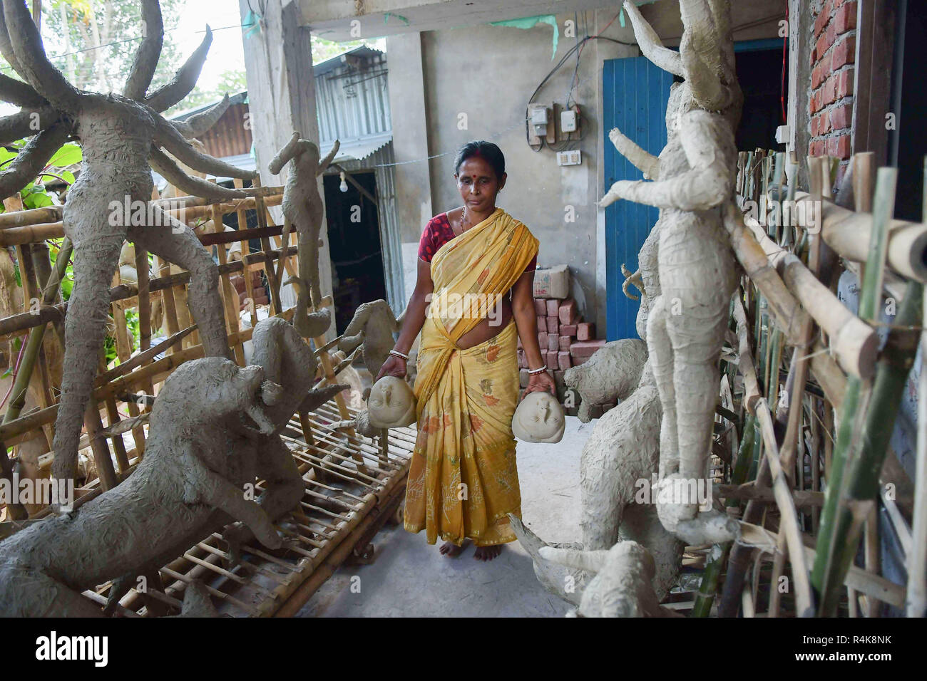 Un artiste indien vu porter les visages de l'idole d'argile déesses Durga, l'avant de la Durga Puja festival au studio à Agartala. Durga Puja, le festival hindou annuel qui implique l'adoration de la déesse Durga, qui symbolise la puissance et le triomphe du bien sur le mal dans la mythologie hindoue, culmine dans l'immersion du corps des idoles dans l'eau. Banque D'Images