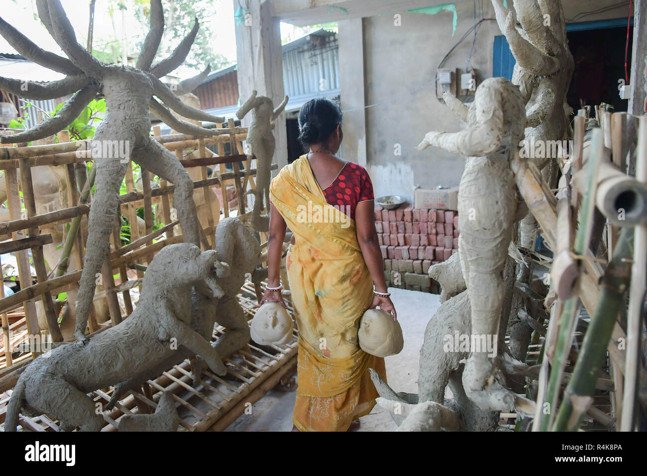 Un artiste indien vu porter les visages de l'idole d'argile déesses Durga, l'avant de la Durga Puja festival au studio à Agartala. Durga Puja, le festival hindou annuel qui implique l'adoration de la déesse Durga, qui symbolise la puissance et le triomphe du bien sur le mal dans la mythologie hindoue, culmine dans l'immersion du corps des idoles dans l'eau. Banque D'Images