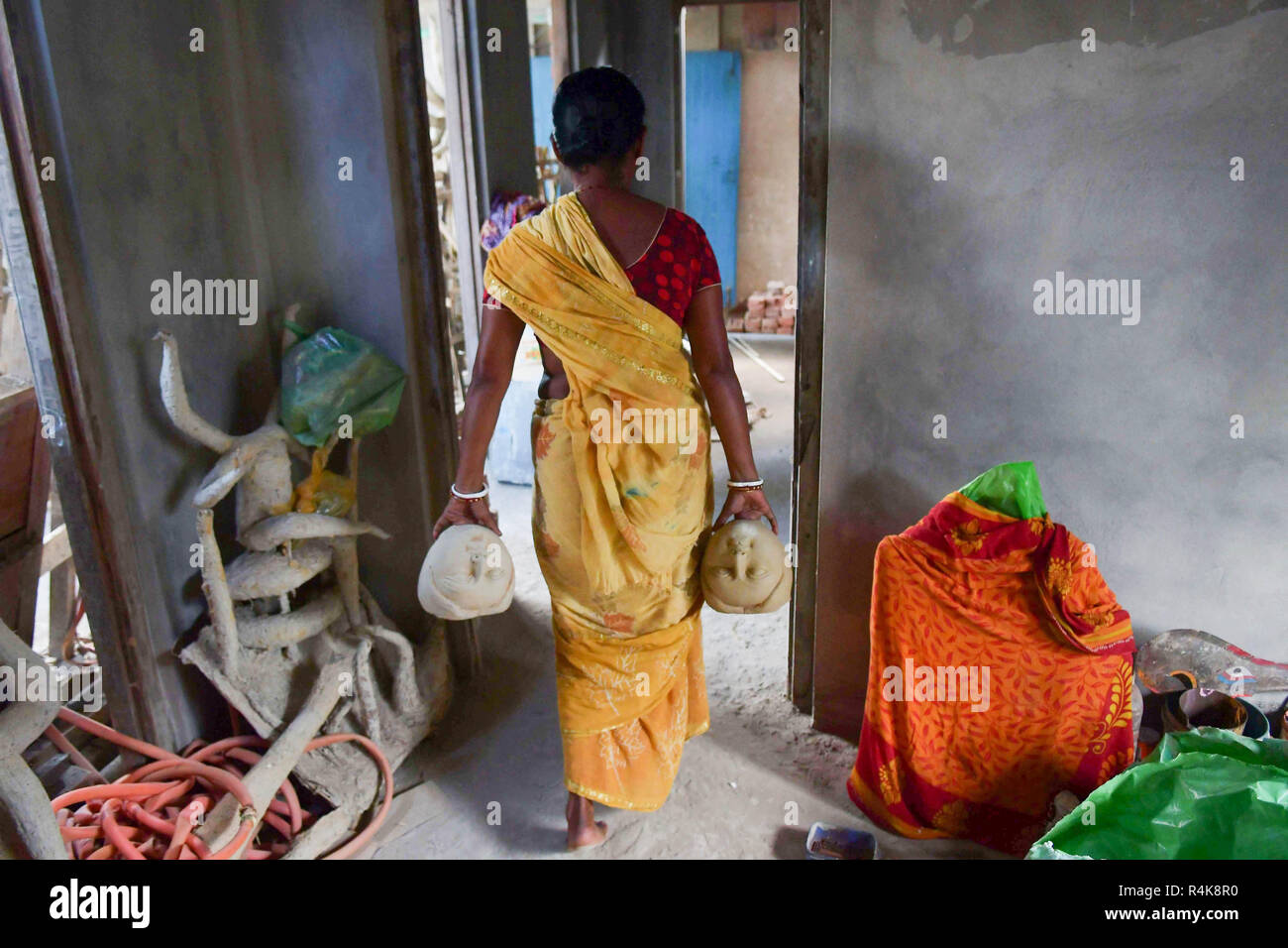 Un artiste indien vu porter les visages de l'idole d'argile déesses Durga, l'avant de la Durga Puja festival au studio à Agartala. Durga Puja, le festival hindou annuel qui implique l'adoration de la déesse Durga, qui symbolise la puissance et le triomphe du bien sur le mal dans la mythologie hindoue, culmine dans l'immersion du corps des idoles dans l'eau. Banque D'Images