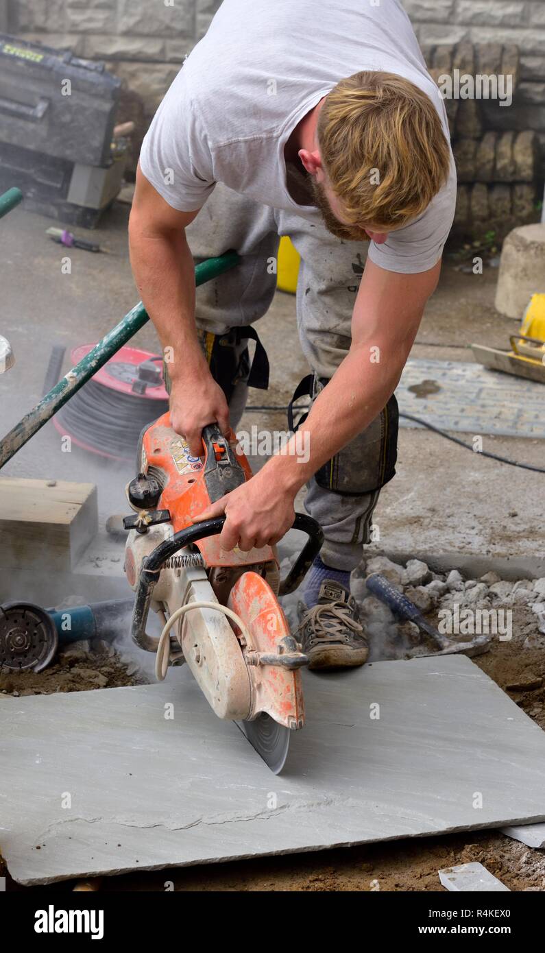 Dalle pavage en pierre d'être coupé avec une scie circulaire alimenté essence Banque D'Images