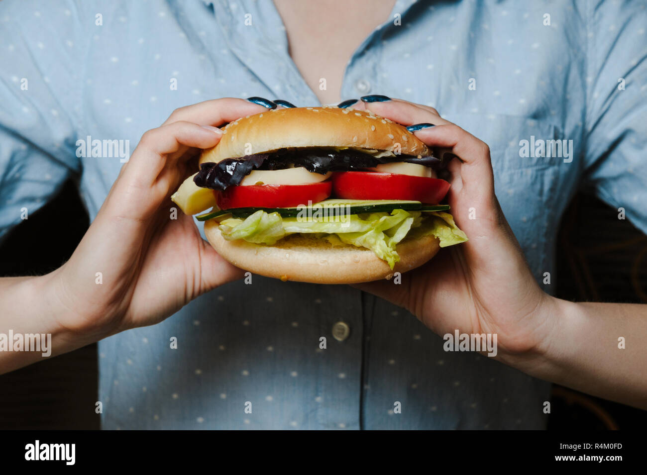 Burger végétarien tenant dans femme fille mains à fond noir Banque D'Images