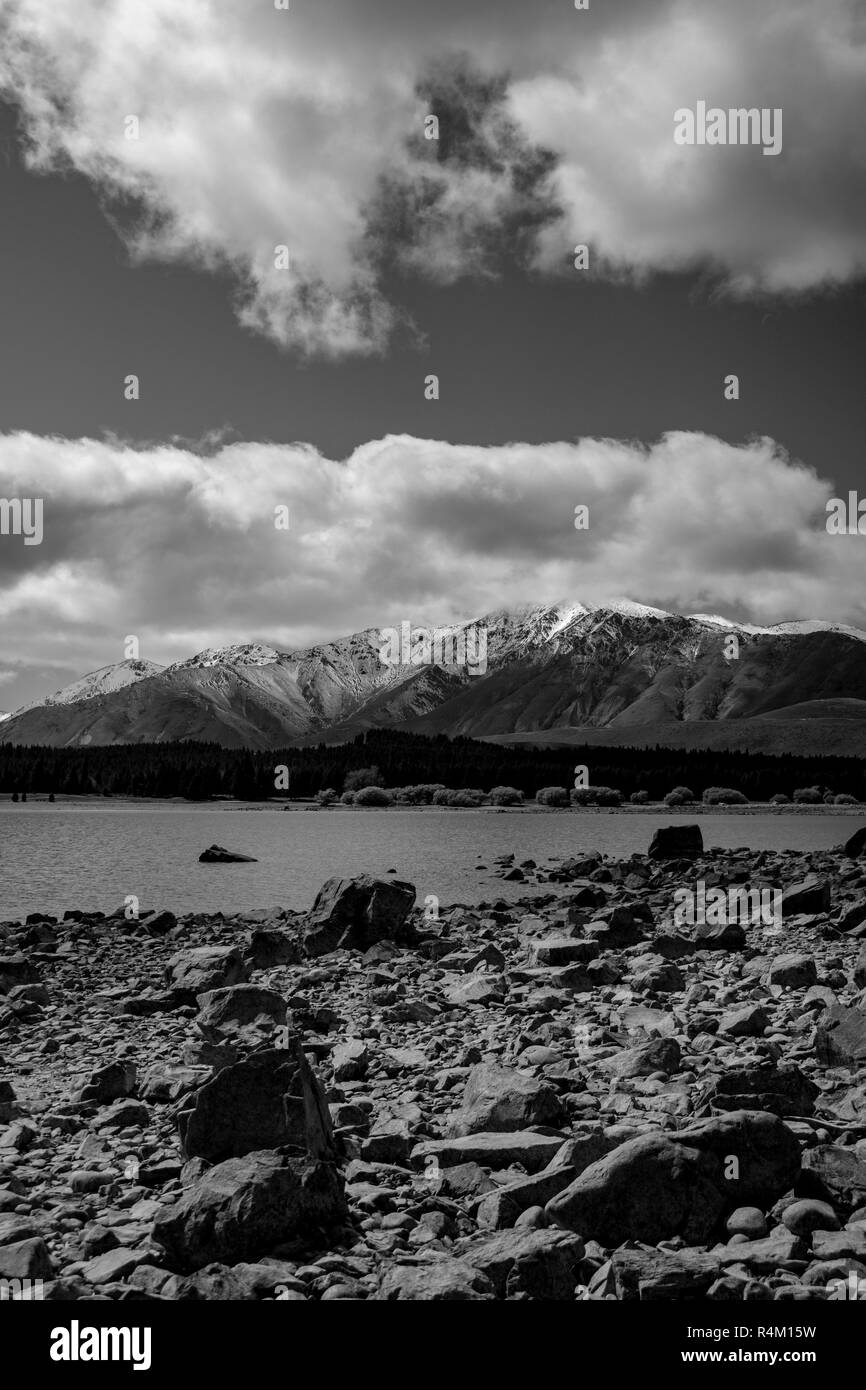 Rocky Monochrome Ruataniwha Inlet estran à marée basse avec de la neige sur les montagnes lointaines dans dramaitc nuages à Collingwood, New Zealan Tasman Bay Banque D'Images