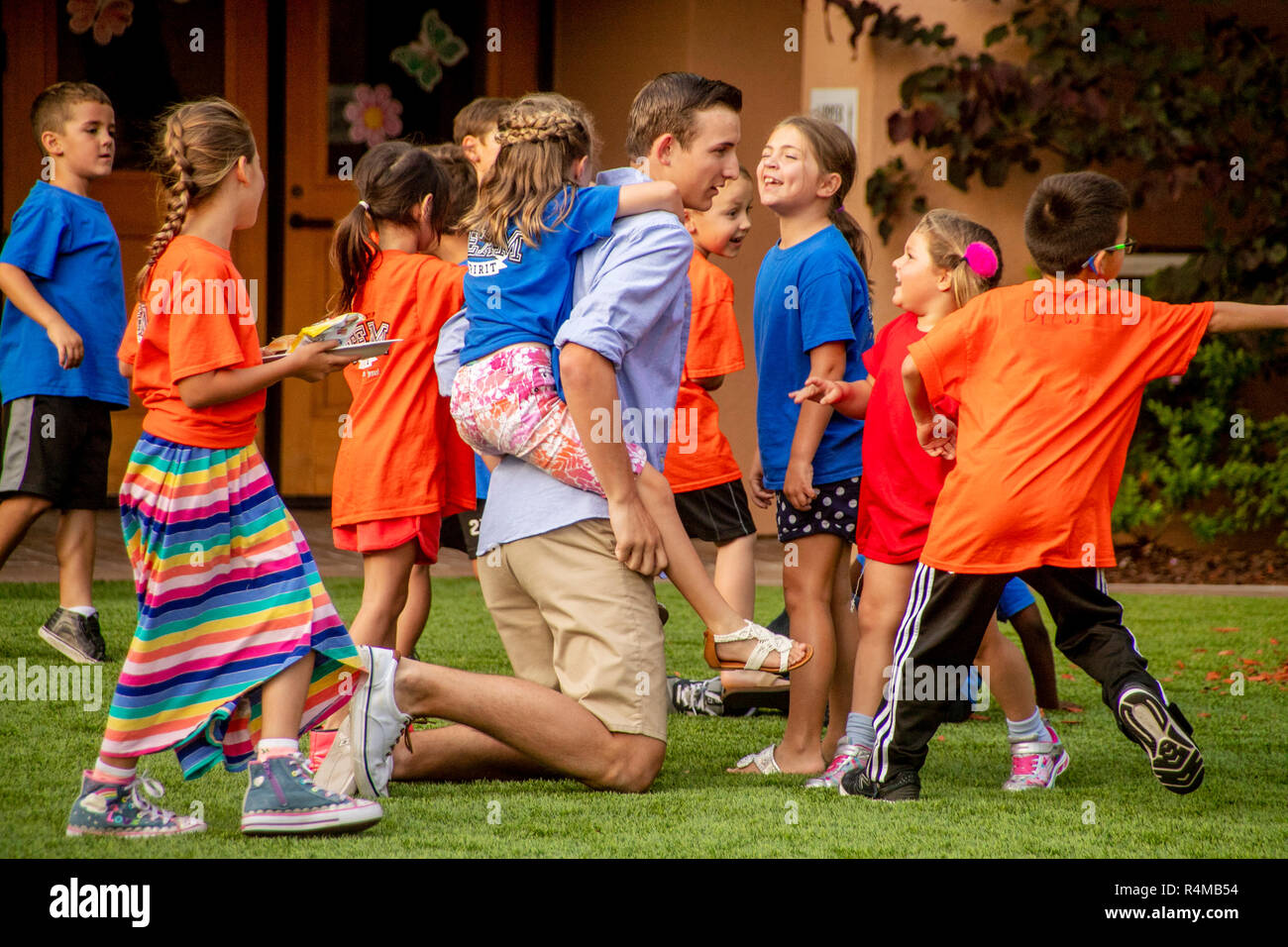 Un père donne à sa fille un piggyback ride tout en jouant avec d'autres enfants des paroissiens sur la pelouse d'une Laguna Niguel, CA, l'église catholique. Banque D'Images