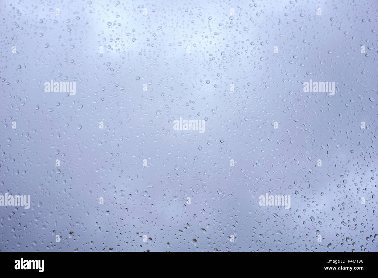 Ciel nuageux Ciel bleu derrière la fenêtre en verre plein de chute de pluie. Motif de fond des gouttes d'eau Banque D'Images