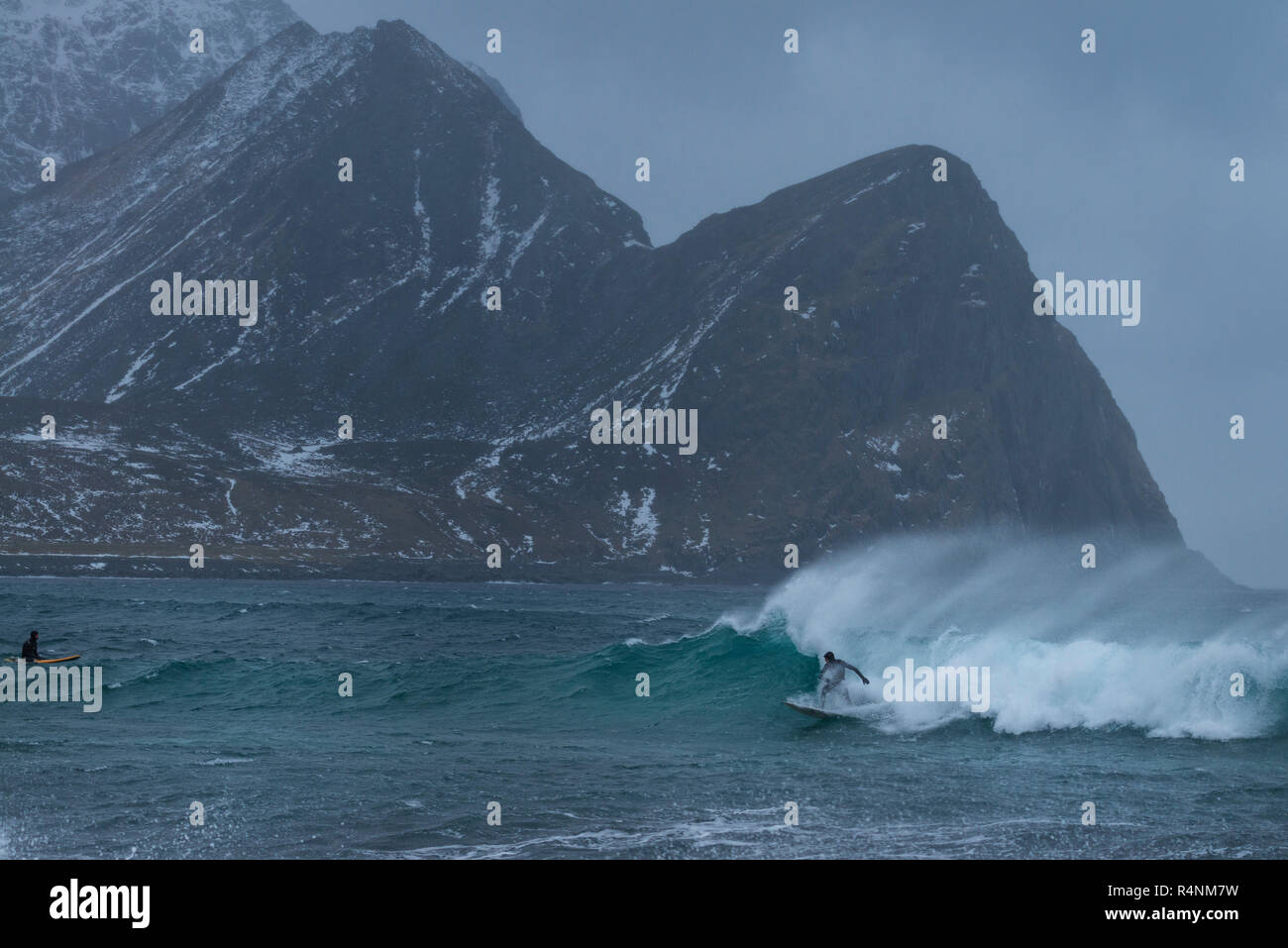 Vue éloignée sur la mer, deux surfeurs à Unstad beach, Vestvagoya, îles Lofoten, Norvège Banque D'Images
