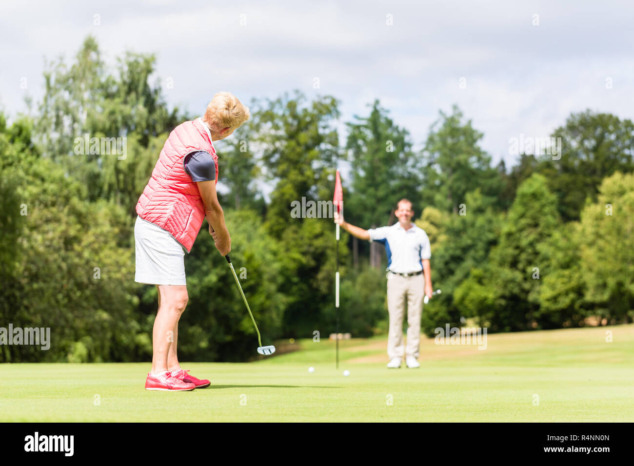 Senior woman practicing with golf pro Banque D'Images