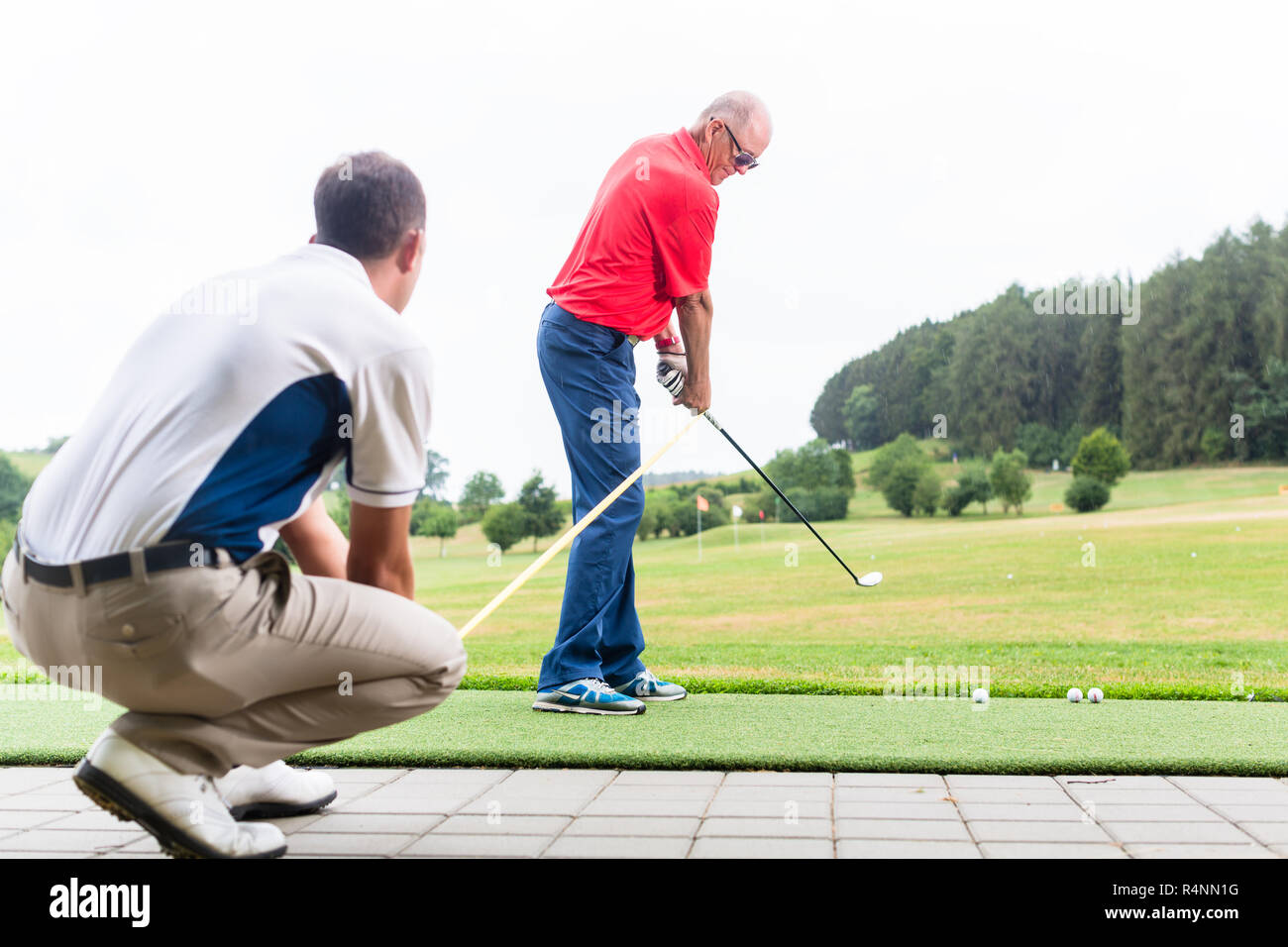 Entraîneur de Golf en collaboration avec joueur de golf sur practice Banque D'Images