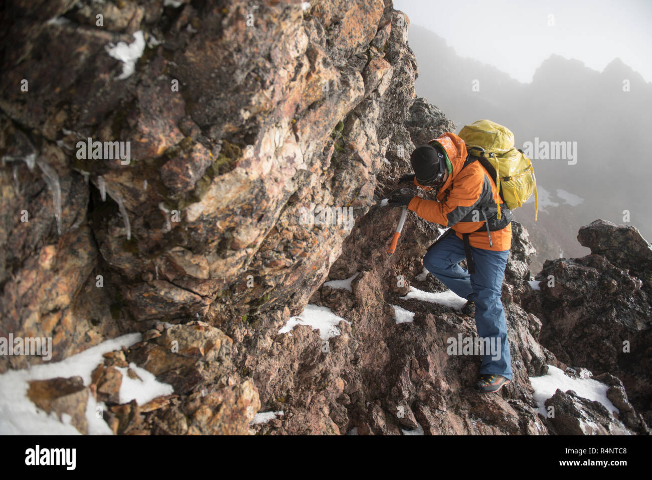 Un homme grimpe à travers une section rocheuse à l'aide d'un piolet, ou piolet, sur son ascension de l'Iztaccihuatl volcanoe Izta-Popo Zoquiapan au parc national dans la région de Puebla, Mexique Banque D'Images