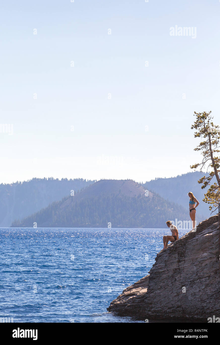 Vue éloignée de l'homme et de la femme en maillot de bain sur la rive du lac de cratère, Oregon, USA Banque D'Images