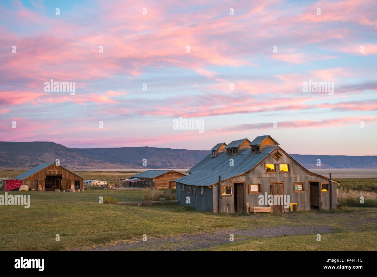 Une ancienne grange située dans un champ d'herbe sous un coucher de soleil rose et bleu ciel, été Lac, Oregon, USA Banque D'Images