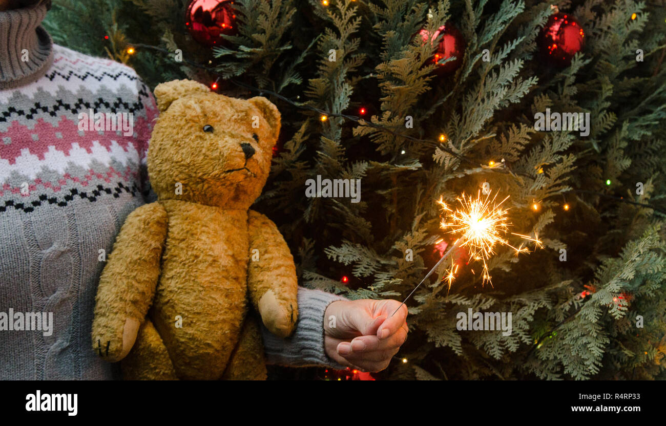 Scène de Noël - femme tenant l'ours en peluche et sparkler avant Noël tree Banque D'Images