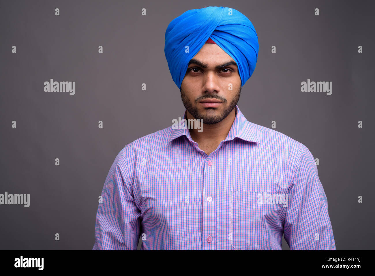 Beau jeune homme d'affaires indien portant turban contre ba gris Banque D'Images