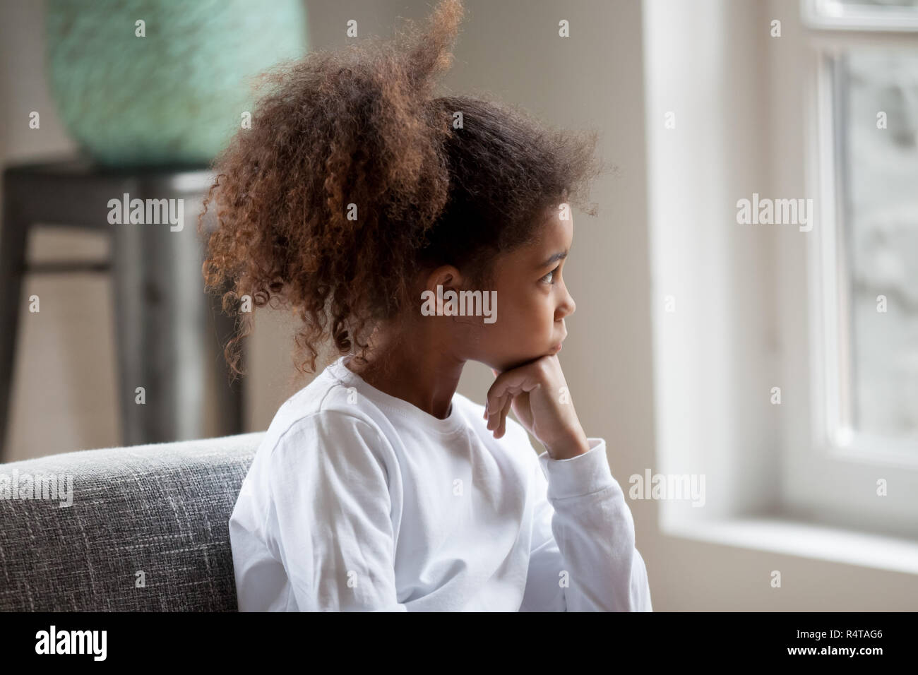 Thoughtful African American girl à la fenêtre en âge préscolaire Banque D'Images