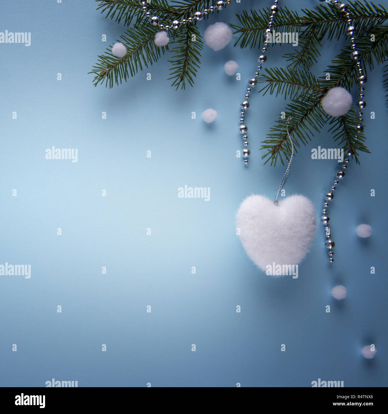 La composition avec les branches de sapin, décoration de Noël en forme de coeur blanc, blanc de neige artificielle et chaîne couleur argent sur papier bleu. Squ Banque D'Images