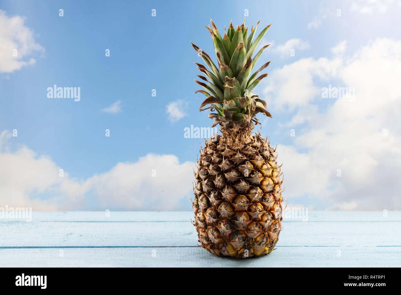 Ananas bio fruits sur une table de bois contre un ciel bleu avec des nuages, copy space Banque D'Images