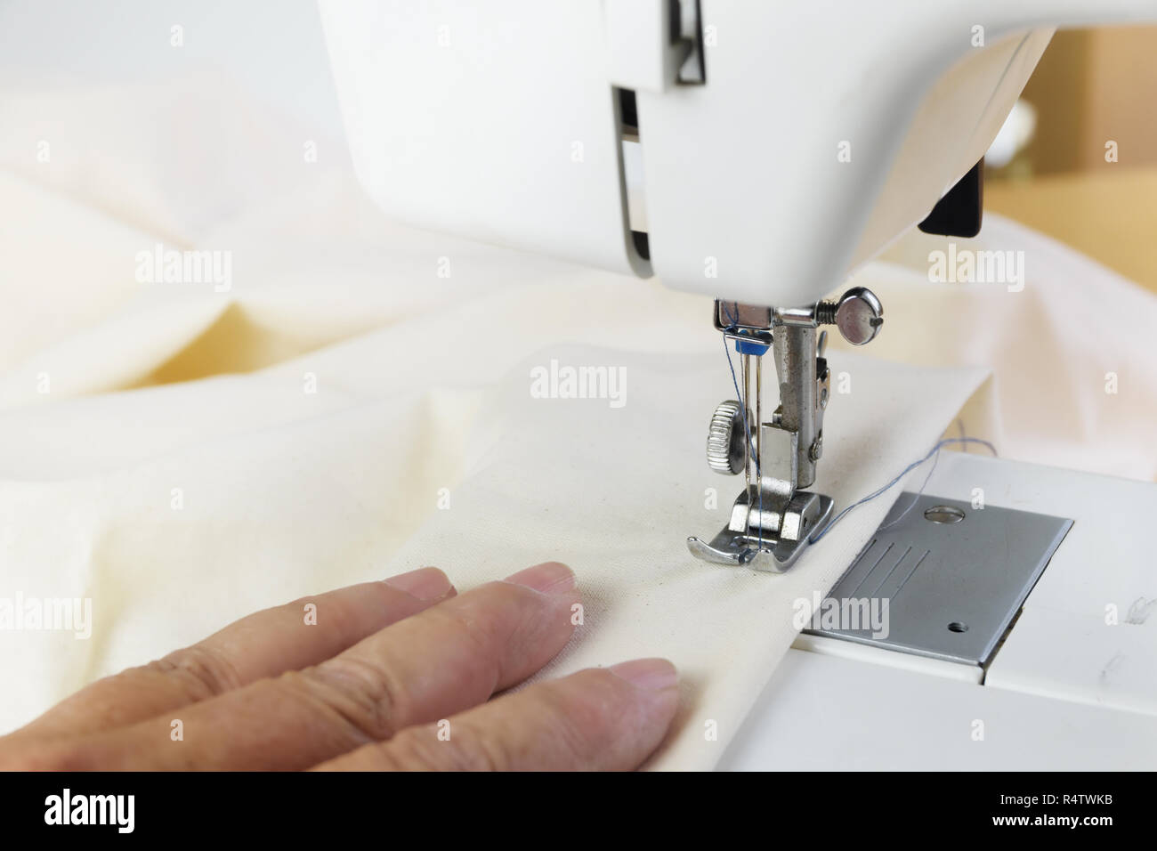 Vous-même à coudre avec une machine à coudre hobby, conduit à la main le tissu blanc sous le pied presseur, Close up avec copie espace étroit, de mise au point sélectionnée, dept Banque D'Images