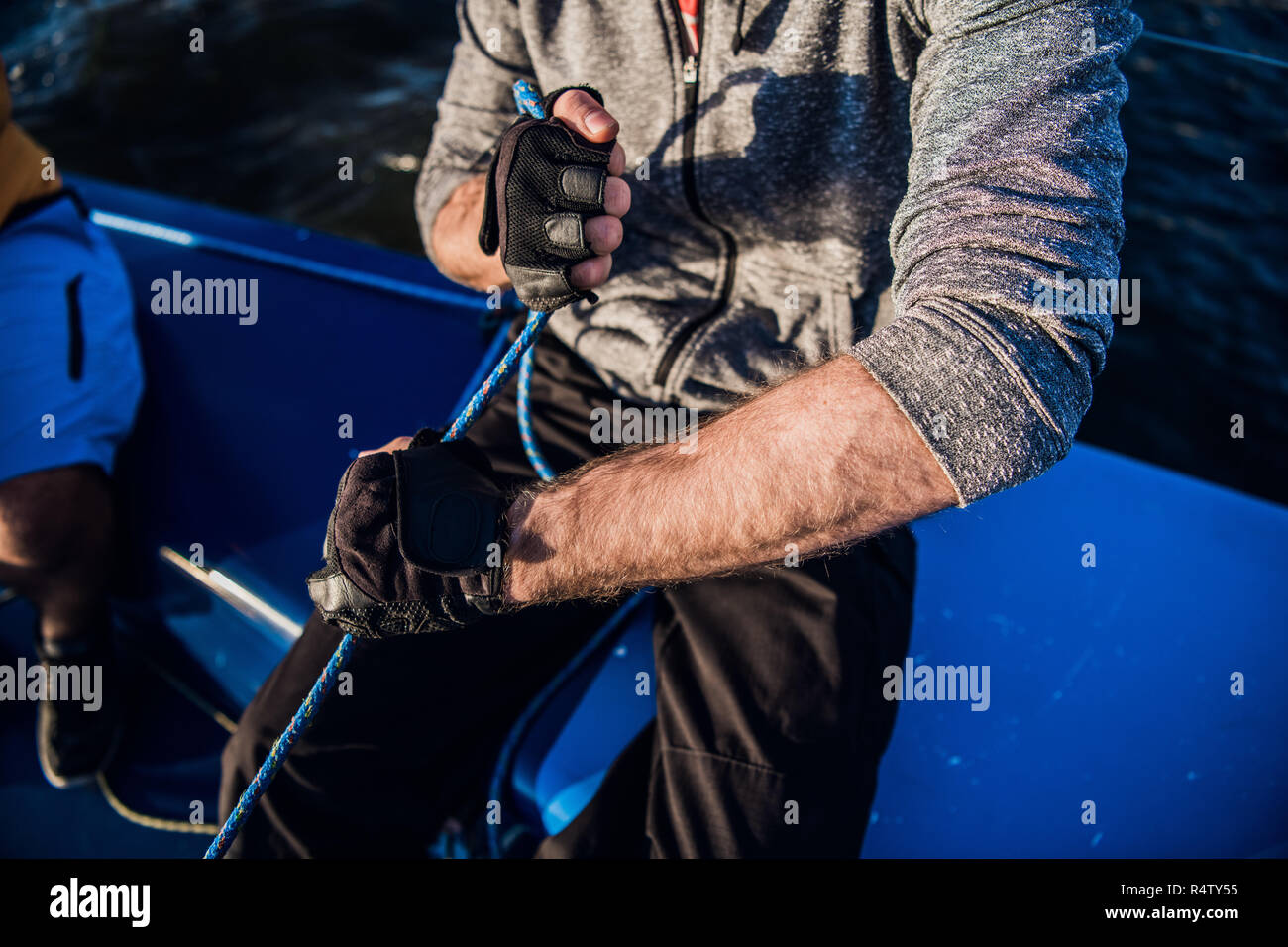 Close up de vents marin aroung en utilisant la corde de poignée pour l'enroulement. Il travaille avec les deux mains. Jeune homme se dresse sur yacht. Il est fort Banque D'Images
