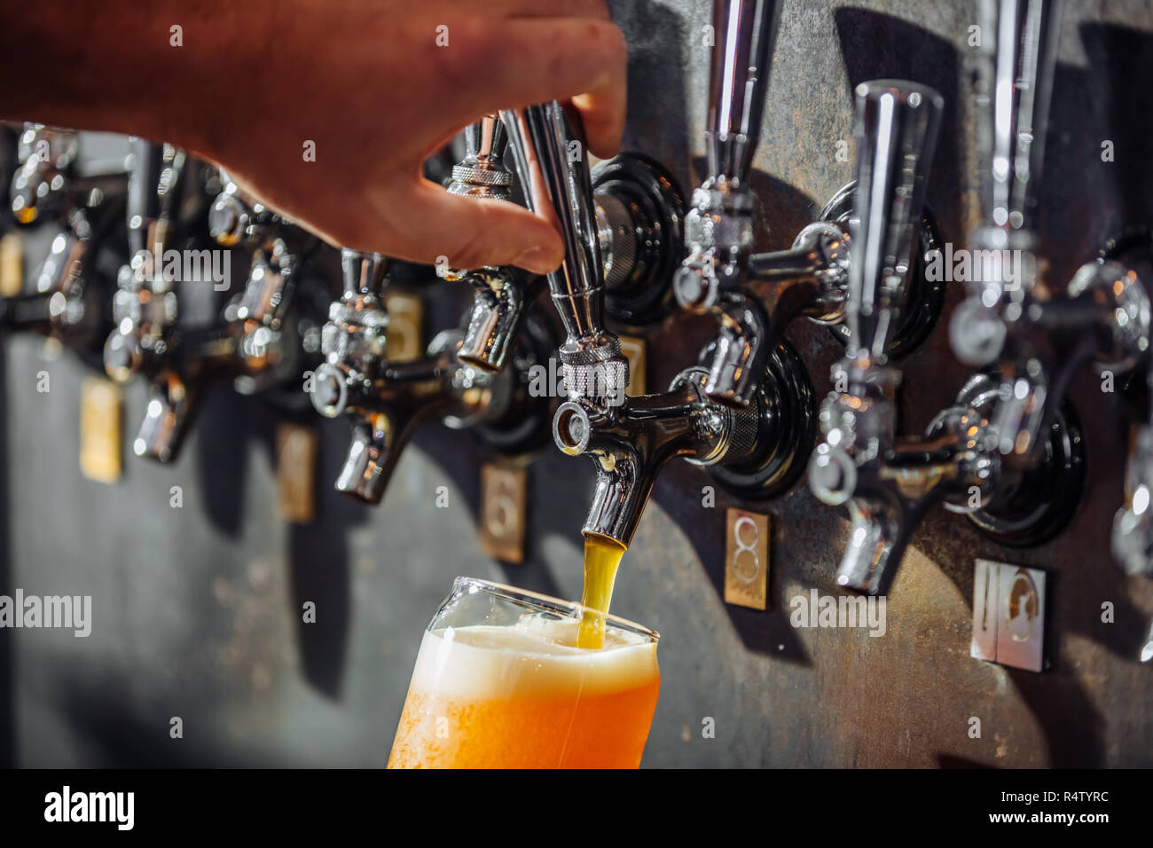 Un Bartender Pouring Beer d'une rangée de robinets dans un pub Banque D'Images