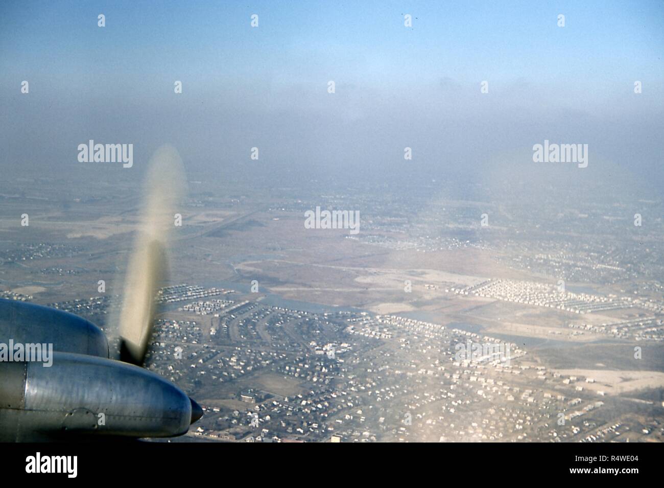 Vue aérienne vers le nord-ouest des quartiers de Woodmere, Parc Woodmere, Saddle Ridge, North Woodmere, et Valley Stream, dans la zone de cinq villes du comté de Nassau, Long Island, New York, mars 1959. En bas à gauche est le moteur à hélice d'un avion de Swissair DC 7C à l'approche de l'Aéroport International de New York Idlewild juste hors du cadre. Visible en bas à l'arrière-plan au-delà du nez du moteur est le bâtiment de l'école Académie Woodmere Saint-laurent au milieu d'une clairière herbeuse entourée par l'habitat résidentiel. Juste au-dessus en diagonale au bord inférieur de la péninsule est Bou Banque D'Images