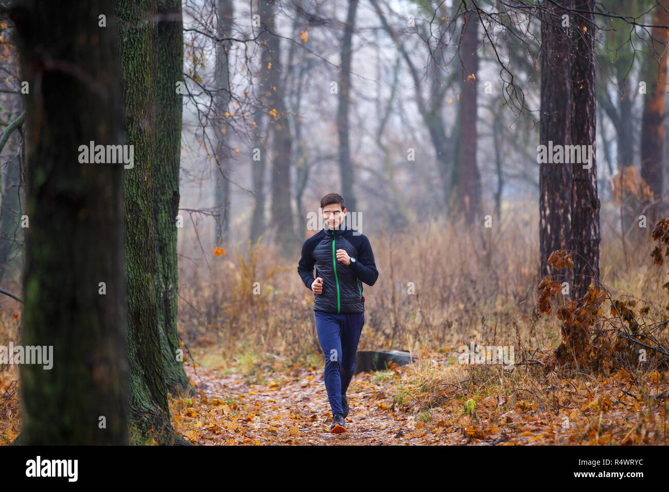 Young man jogging in autumn park le matin. Runner sur le trail running à la fin de l'automne park Banque D'Images
