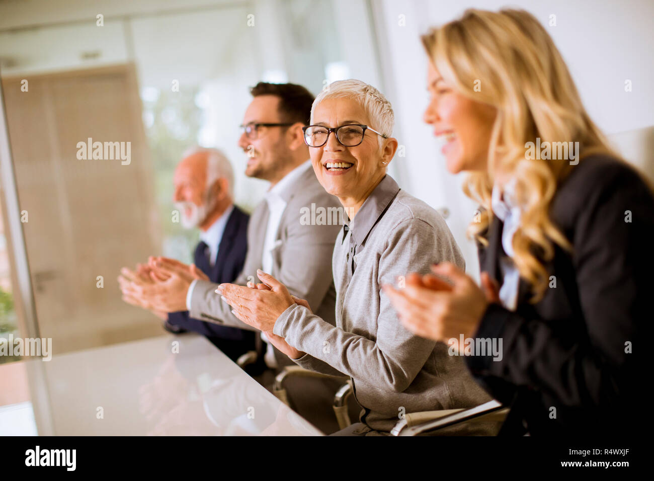 Satisfait de l'équipe entreprises fier clapping hands while sitting in row at office Banque D'Images
