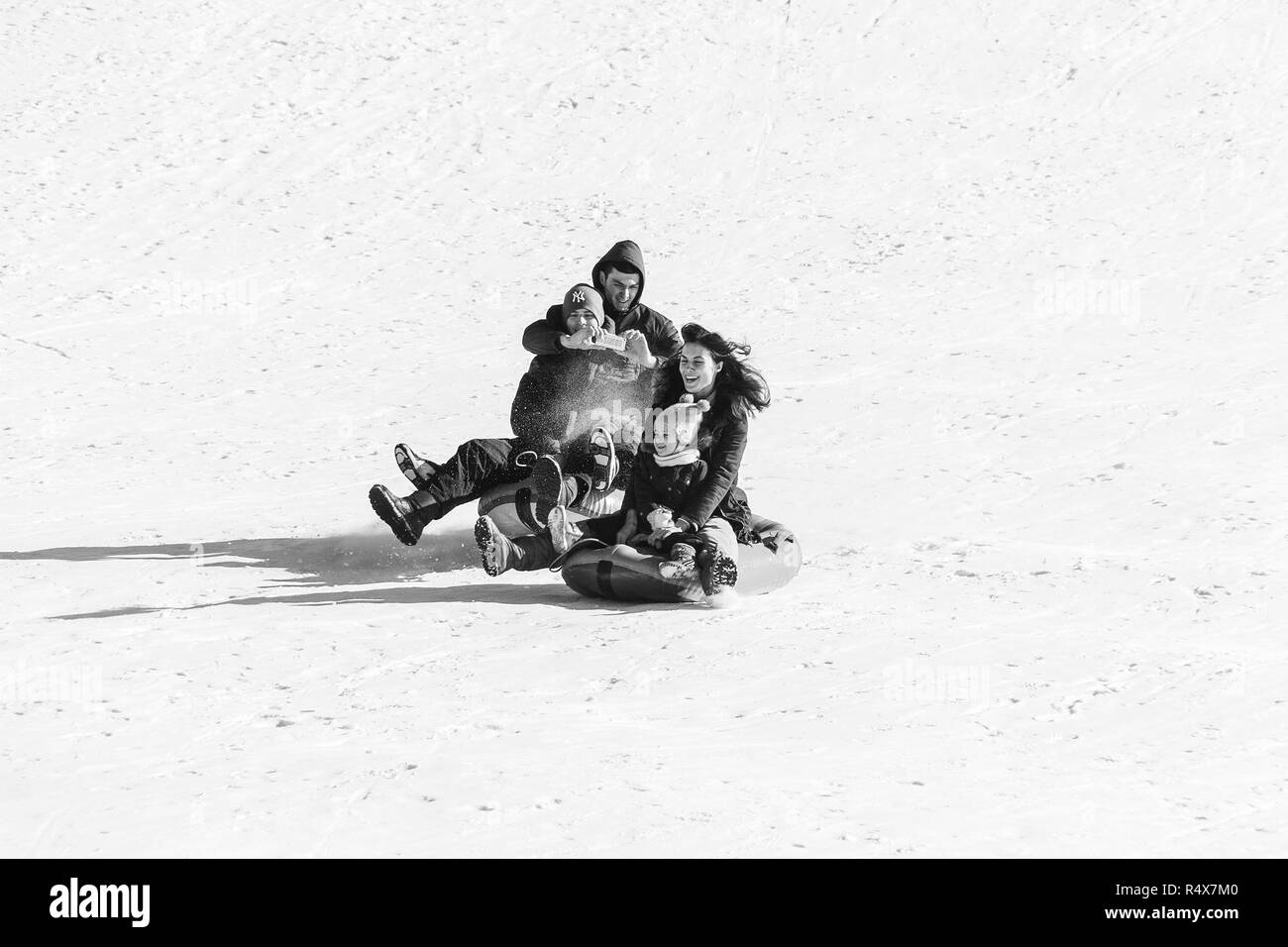 Adygea, Russie - le 23 janvier 2017 : Young happy couple avec enfants sur la luge gonflable sur une pente enneigée, un homme tire une vidéo sur un Banque D'Images