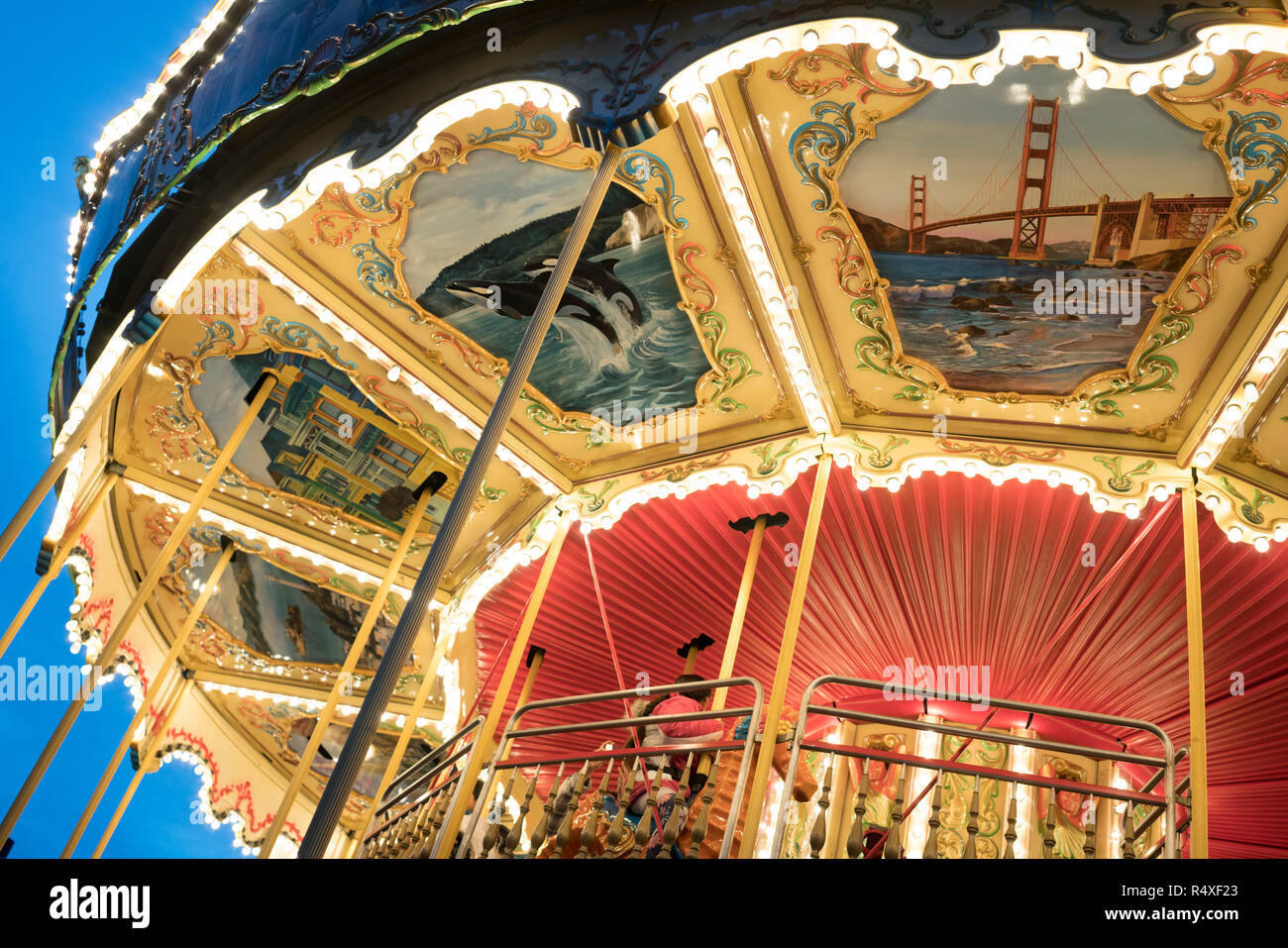 Un vieux Carrousel, peint avec des scènes de la vie de San Francisco dans une fin de journée la lumière, Pier 39, San Francisco, California, USA Banque D'Images