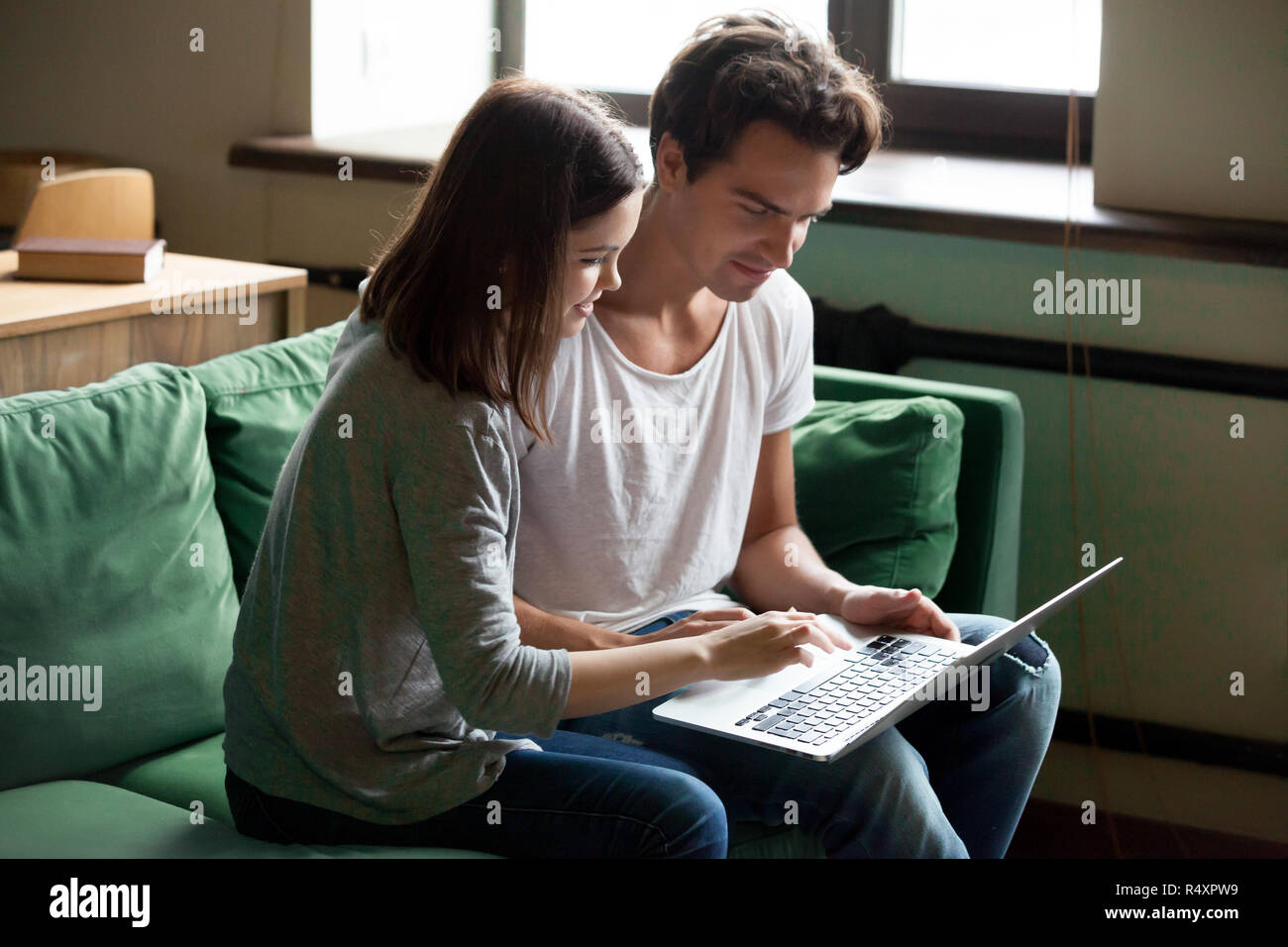 Jeune couple avec laptop sitting on sofa at home Banque D'Images
