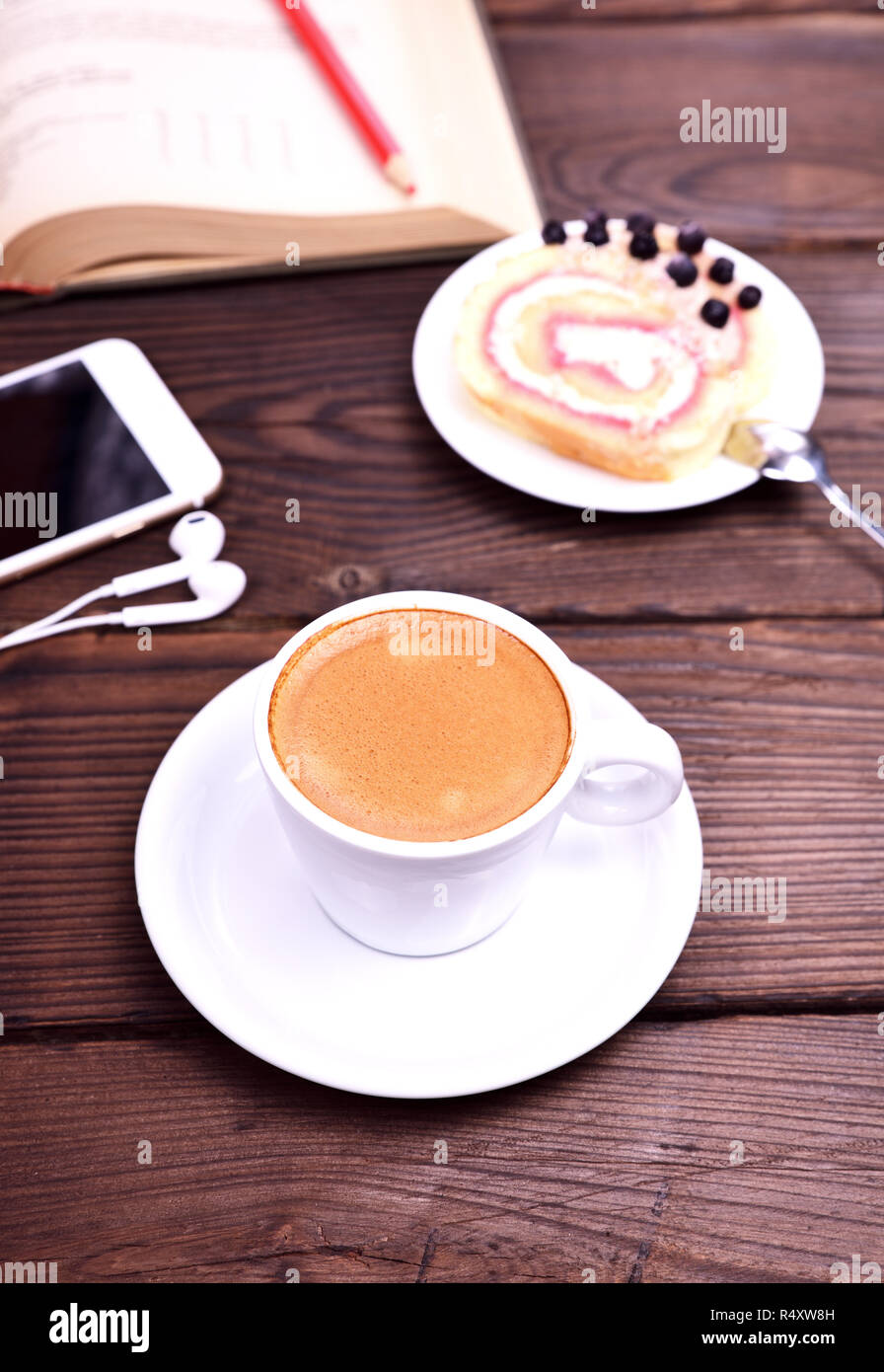 Tasse de café et d'un téléphone mobile sur une table marron Banque D'Images