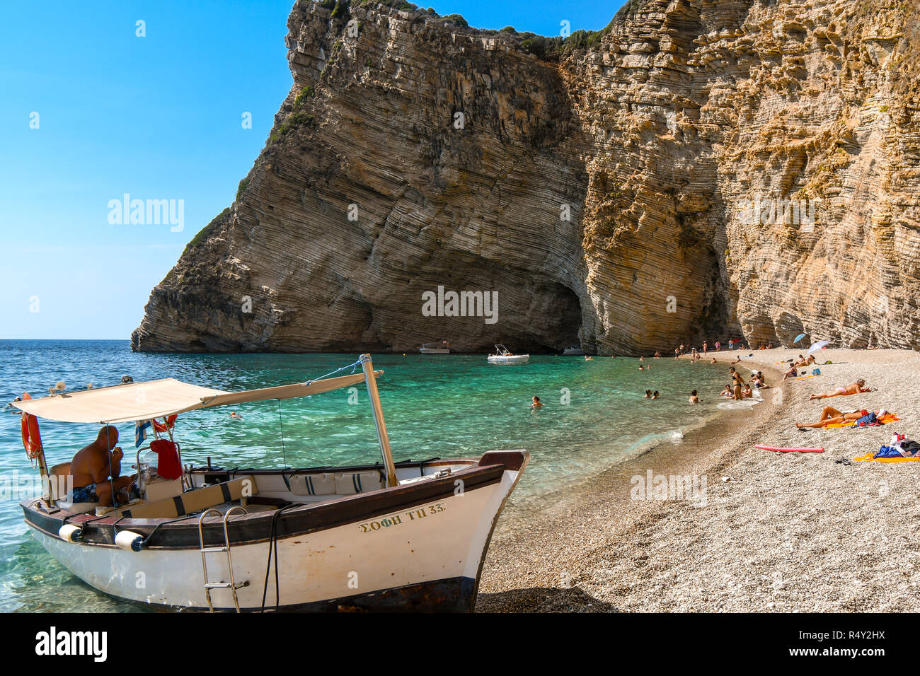 Un bateau attend sur la plage de sable de transport de touristes retour à la ville à partir de la Paradise Beach, également connu sous le nom de Chomi Beach, sur l'île grecque de Corfou Banque D'Images