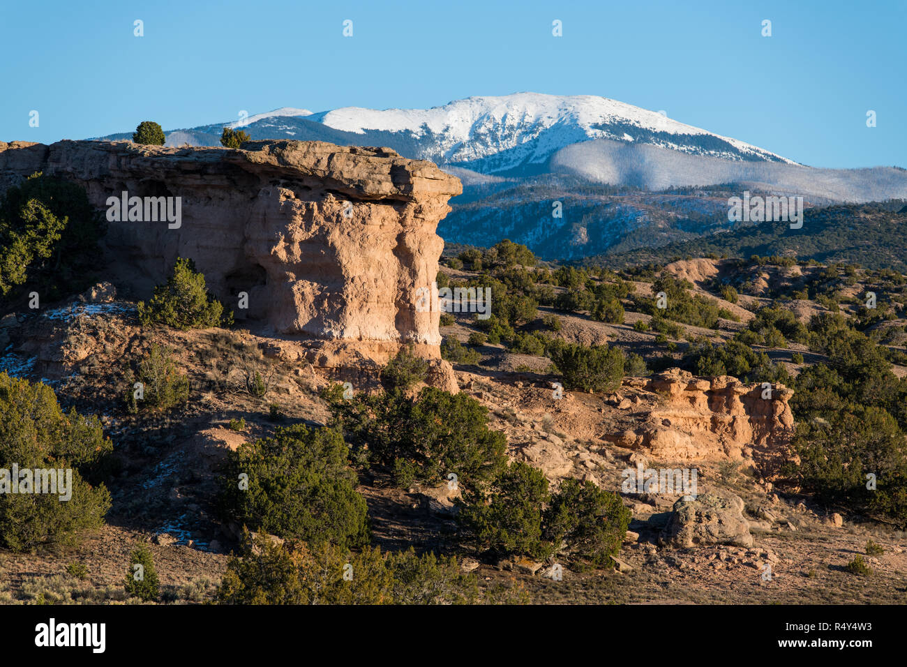Red Rock formation avec les sommets enneigés des montagnes Sangre de Cristo dans la distance près de Santa Fe, Nouveau Mexique Banque D'Images