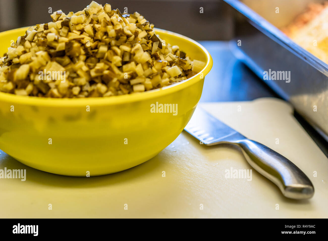 Bol en plastique jaune avec des morceaux de concombres - En plus du couteau, il Set de cuisine Banque D'Images