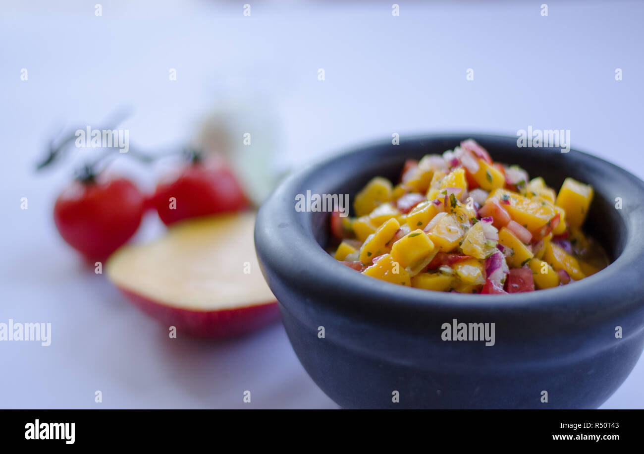 Salsa de mangue dans un bol en pierre avec des ingrédients à l'arrière-plan Banque D'Images Salsa de mangue dans un bol en pierre avec des ingrédients à l'arrière-plan Banque D'Images