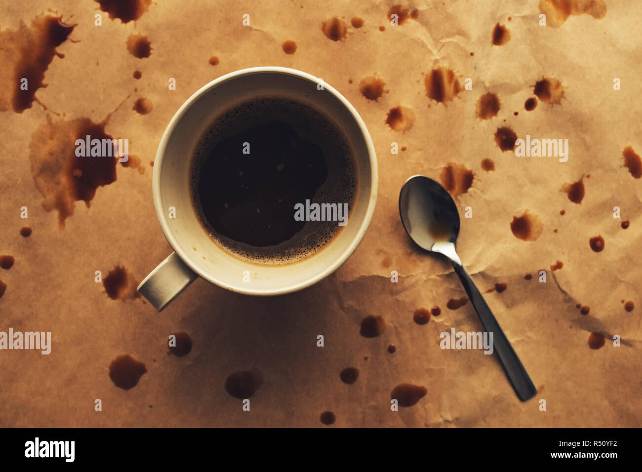 Vue de dessus de la cuillère et la tasse de café avec des touches, les taches et coulures sur la surface du papier Banque D'Images