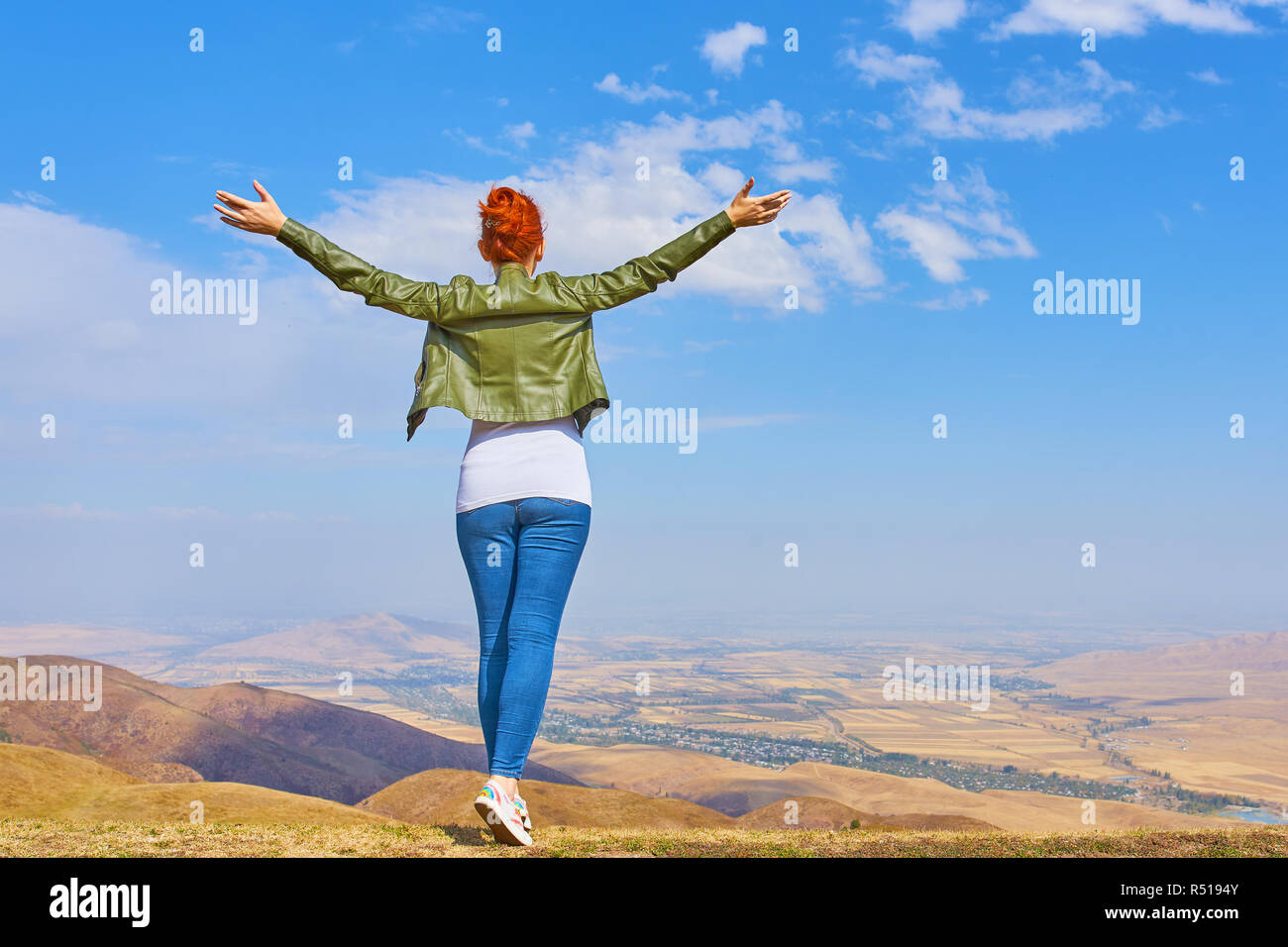 Concept de voyage. Femme dans une montagne debout dans la distance avec son dos à la caméra et ses bras étendu dans la célébration d'une belle journée ensoleillée s Banque D'Images