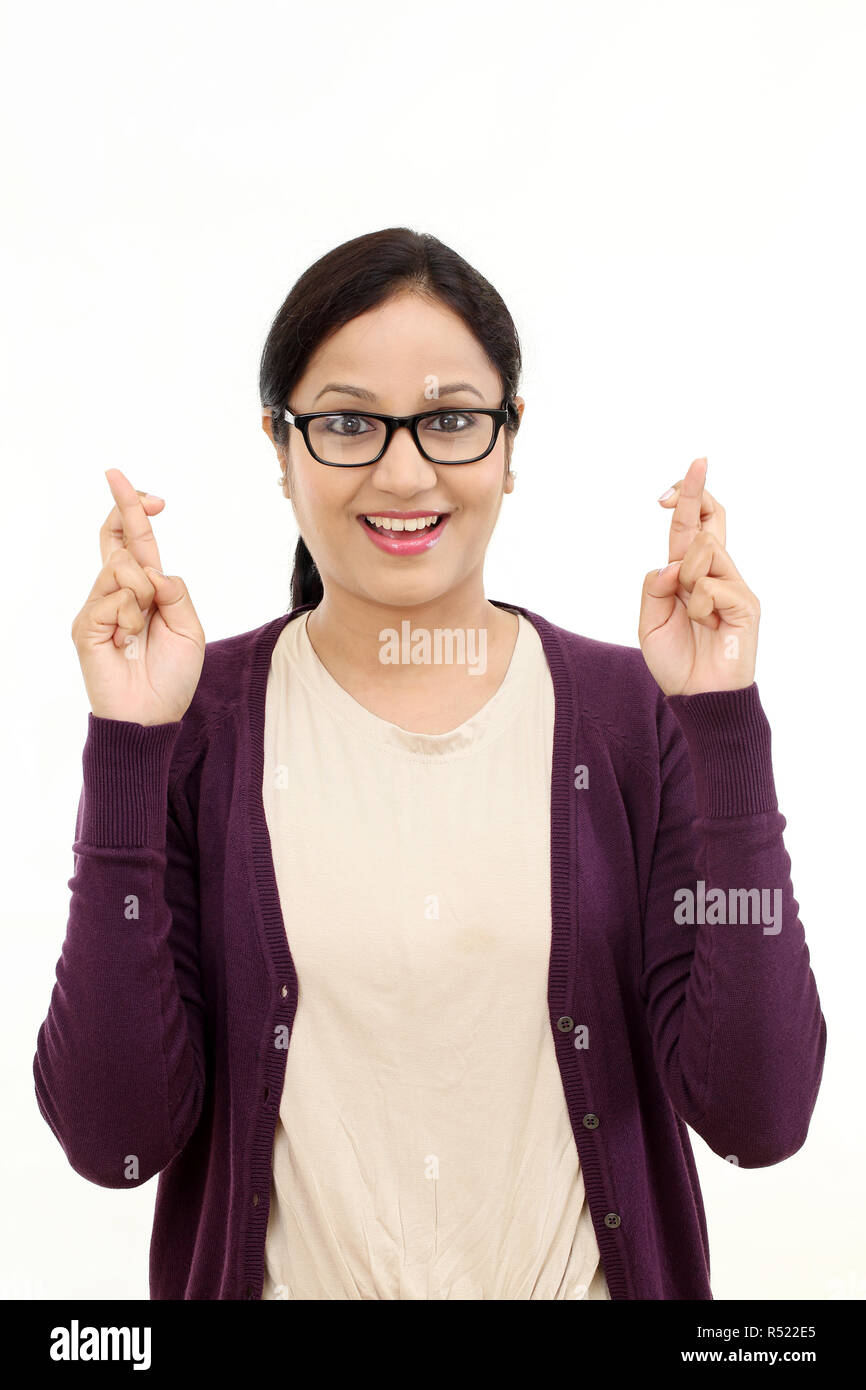 Jeune femme heureuse crossing fingers against white Banque D'Images