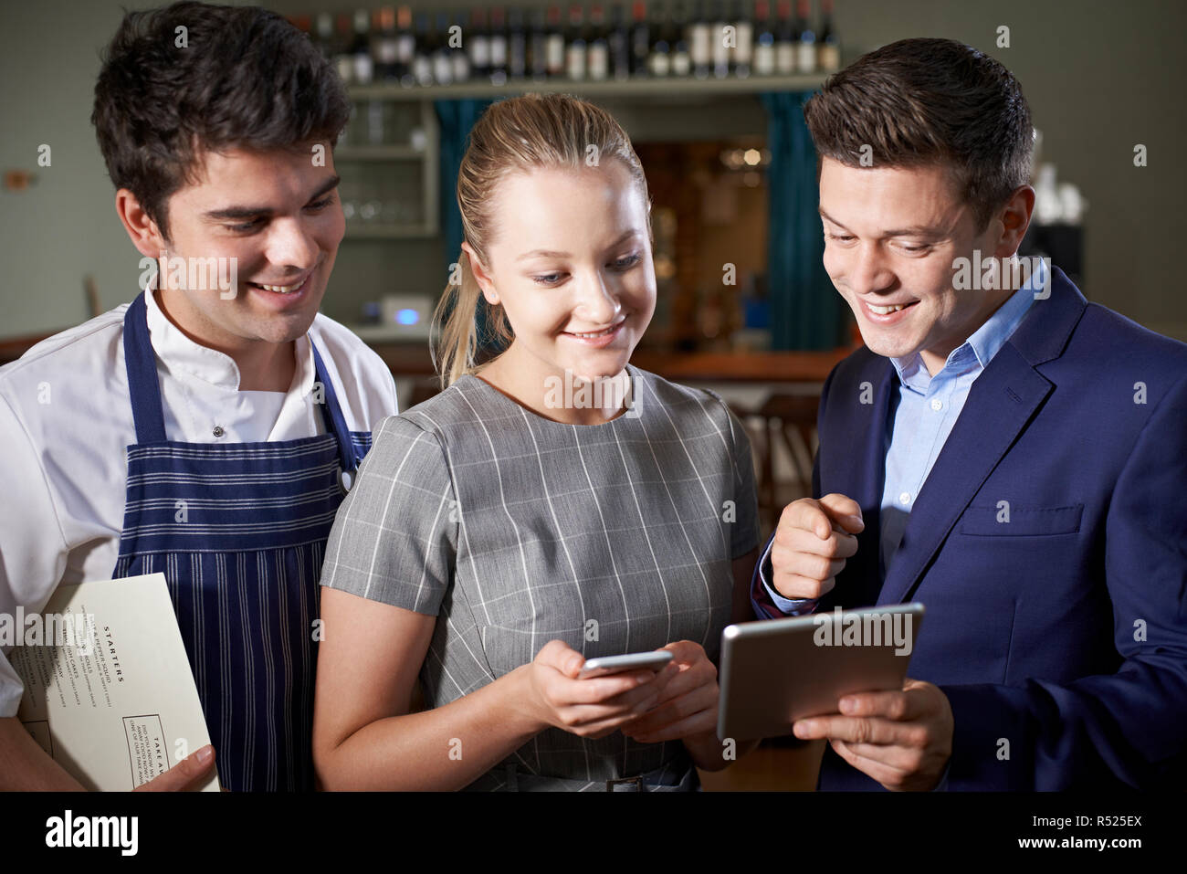 L'équipe de Restaurant Menu Discuter Looking At Digital Tablet Banque D'Images