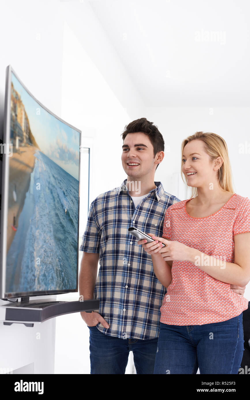 Jeune couple avec un nouveau téléviseur à écran incurvé à la maison Banque D'Images