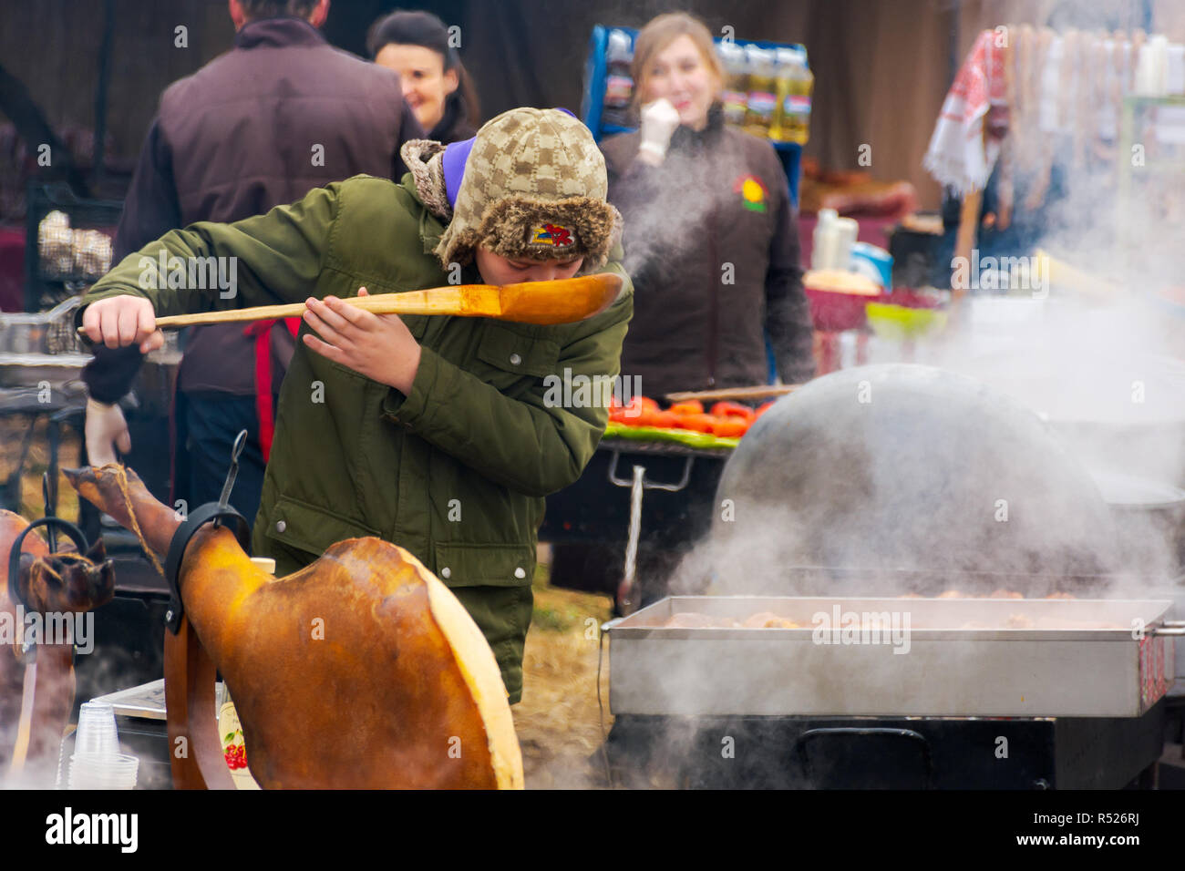 Hecha, Ukraine - Jan 27, 2018 : Porc bouchers la concurrence. chaudron bouillant sur l'épaule de porc. d'incendie sur la table. kid avec de grands plats de dégustation cuillère Banque D'Images