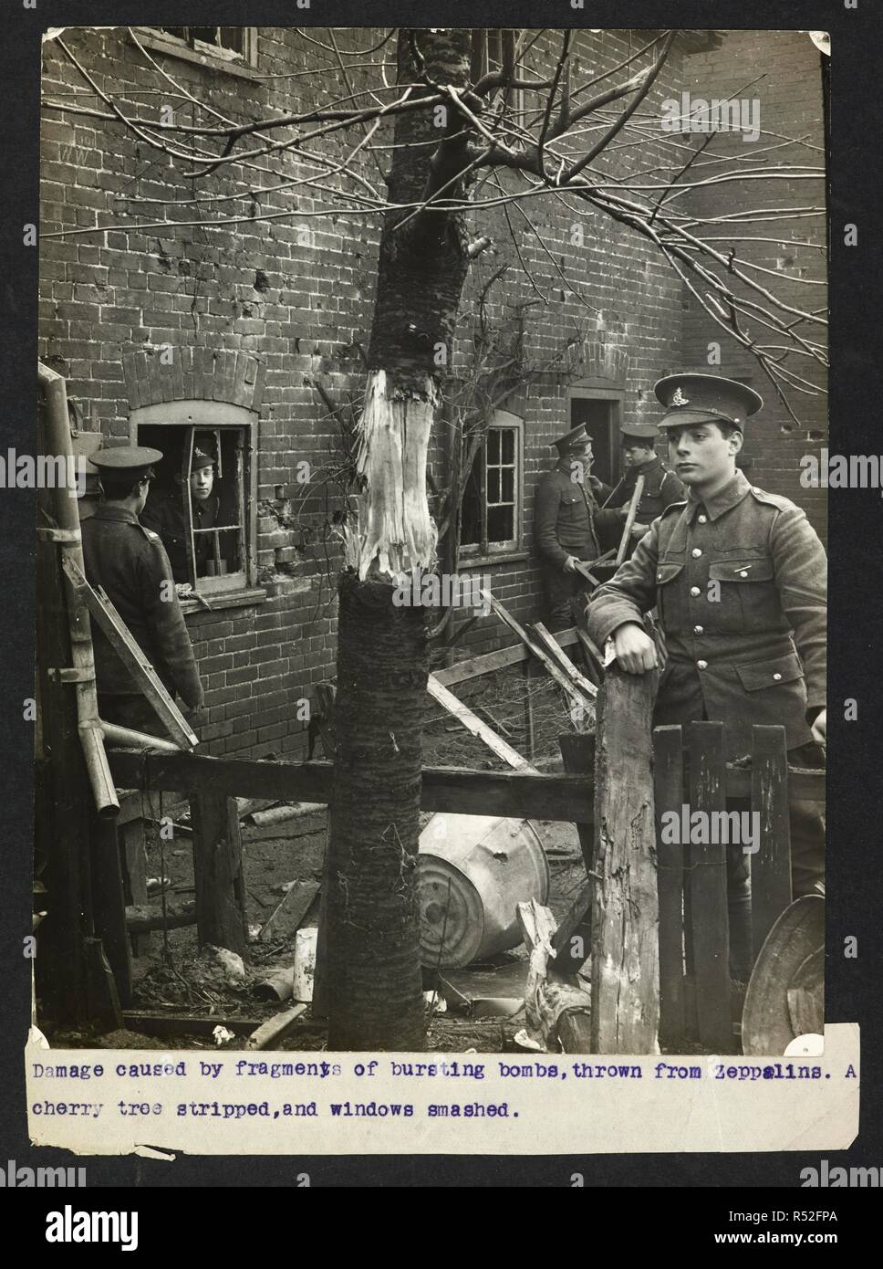 Dommages causés par des fragments d'éclatement des bombes, lancées de zeppelins. Un cerisier dépouillés, et les fenêtres brisées [Angleterre]. Soldats britanniques debout parmi les ruines. Dossier de l'armée indienne en Europe durant la Première Guerre mondiale. 20e siècle, 1915. Argentiques. Source : Photo 24/(28). Langue : Anglais. Auteur : Big Sur, H. D. Banque D'Images