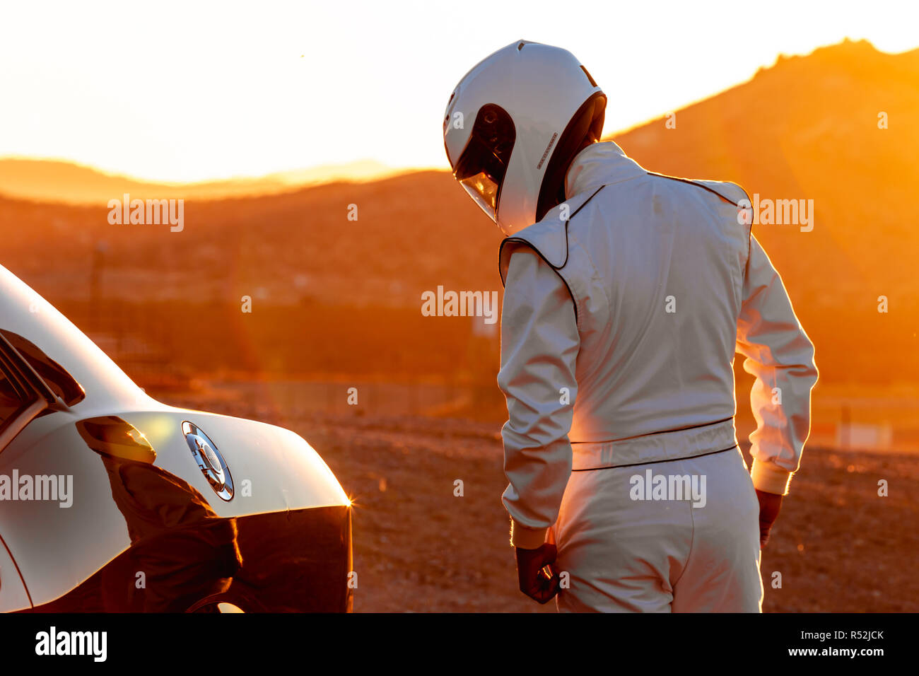 Un port du casque du pilote de voiture de course dans le soleil matinal à la recherche sur sa voiture avant de démarrer Banque D'Images
