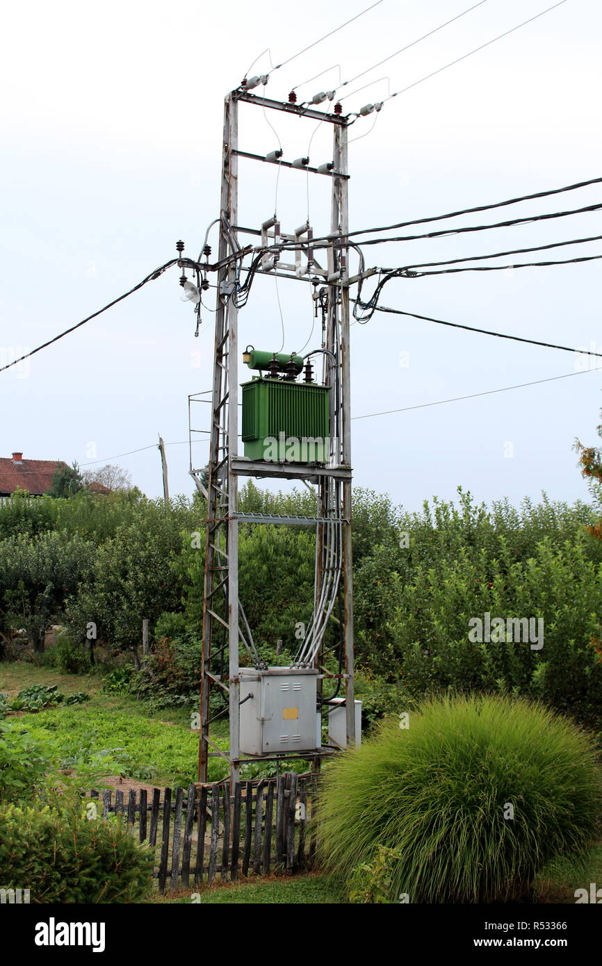 Transformateur de puissance électrique vert avec du gris métal utilite fort sur des poteaux de métal relié à plusieurs câbles électriques Banque D'Images
