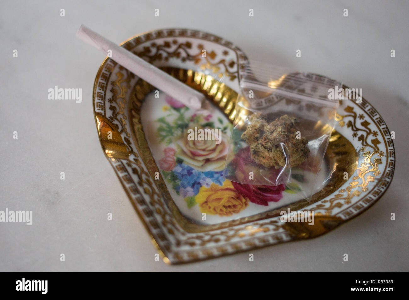 Un petit cendrier en forme de coeur avec un joint et un sac de marijuana. Banque D'Images