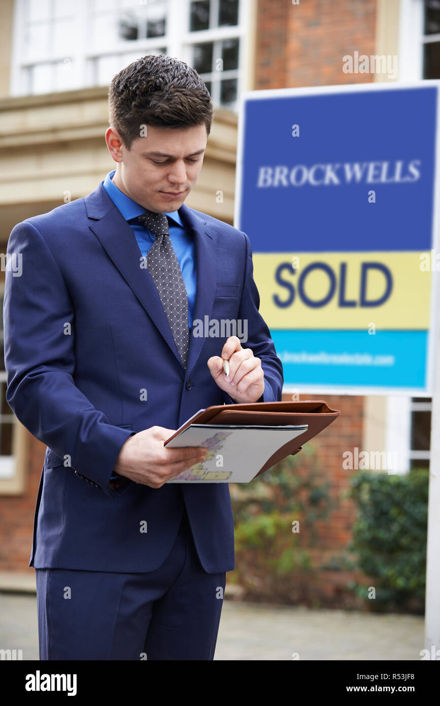 Homme debout à l'extérieur de l'agent immobilier Propriété résidentielle avec Sold Sign Banque D'Images
