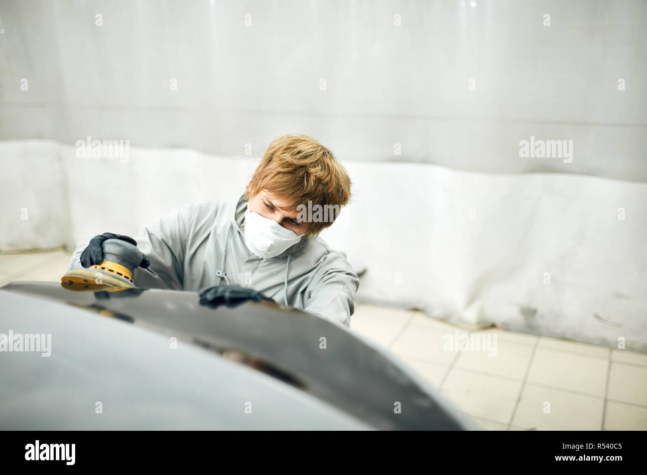 Voiture grince mécanicien pour partie de la peinture. Travaux de réparation de carrosserie auto peinture après accident Banque D'Images