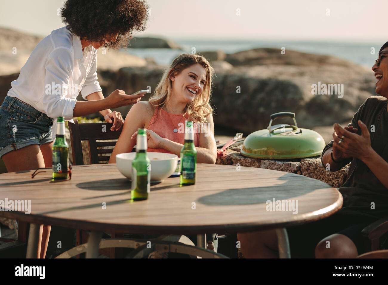 L'homme et de la femme en vacances assis à une table près de la plage de la bière et des collations. profiter Les amis s'amuser parler et rire assis près d'un b Banque D'Images