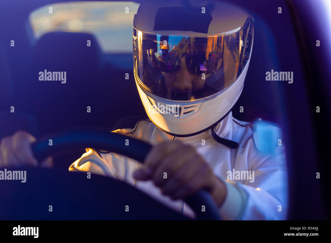 Pilote de course portant un casque au volant de son véhicule sur un matin ensoleillé sur la piste Banque D'Images