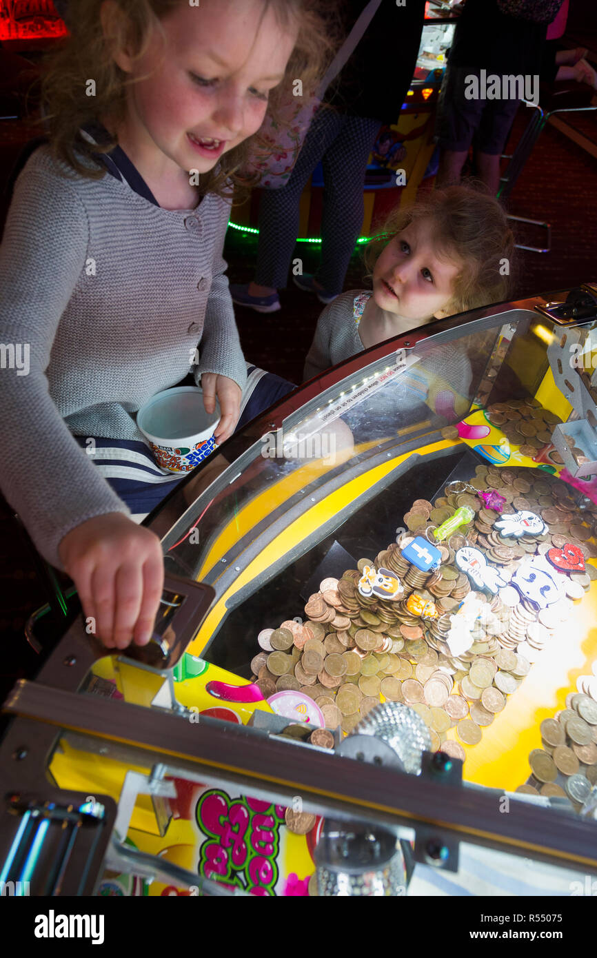 Jeune fille âgée de 6 ans / 6 ans jouant sur un coin pusher traditionnels populaires / pièces poussant en jeu pier arcade fun house. UK. (98). Banque D'Images